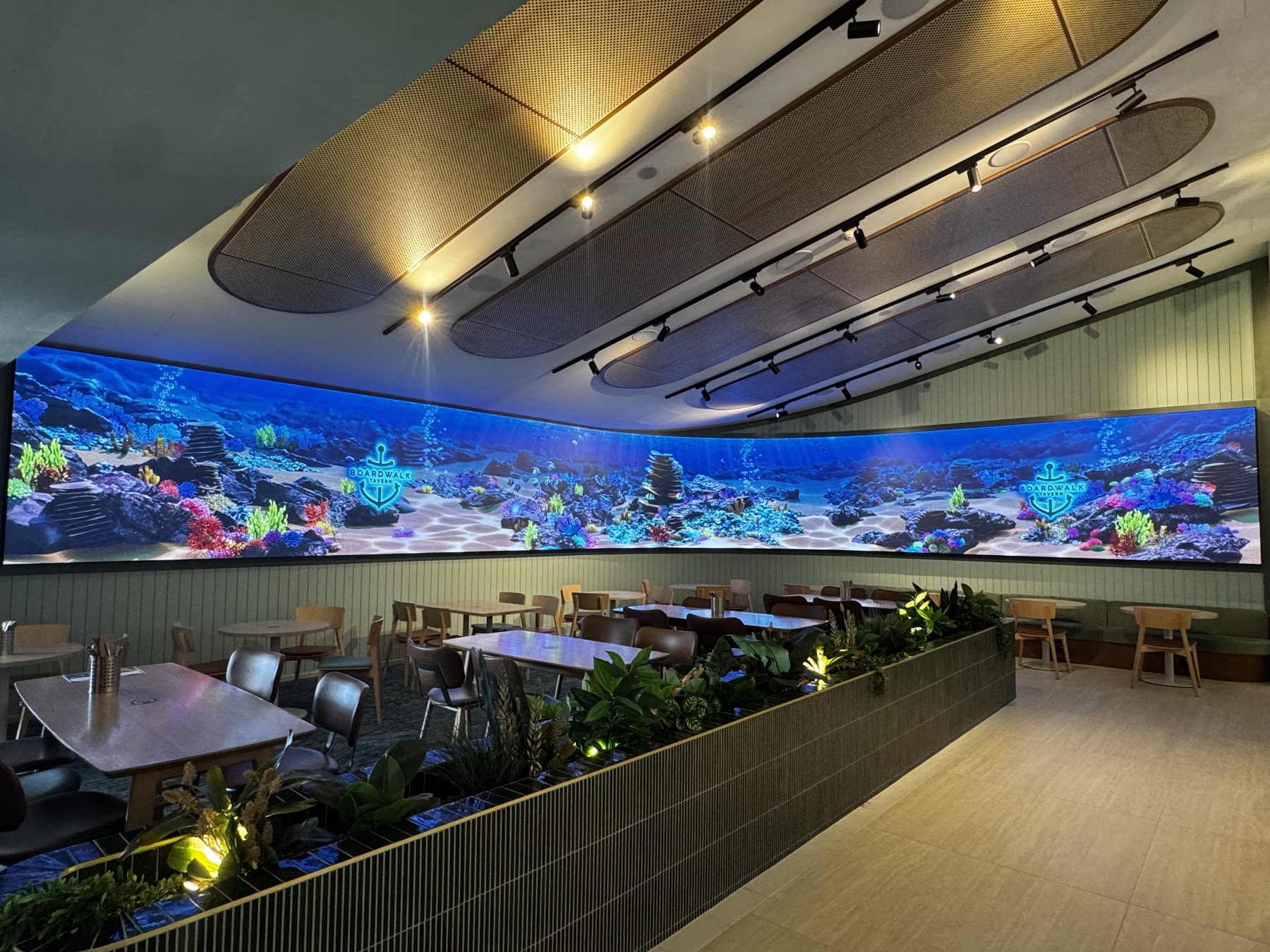 The full ribbon from the far end of the room, the reef scene carrying the tavern's anchor mark twice along its length