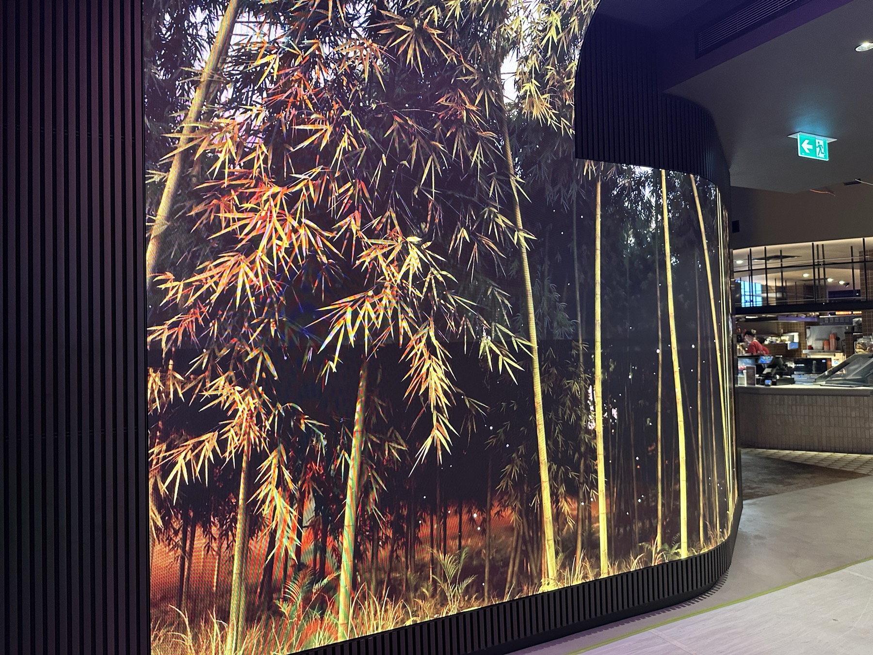 A curved LED wall of golden bamboo wrapping round into the bar area